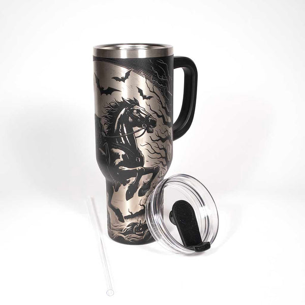 This is a black 40 ounce tumbler with a screw on lid with a drinking hole access and a straw. The laser engraving is of a headless horseman on his trusty steed. With the cover off and straw laying beside the tumbler. 