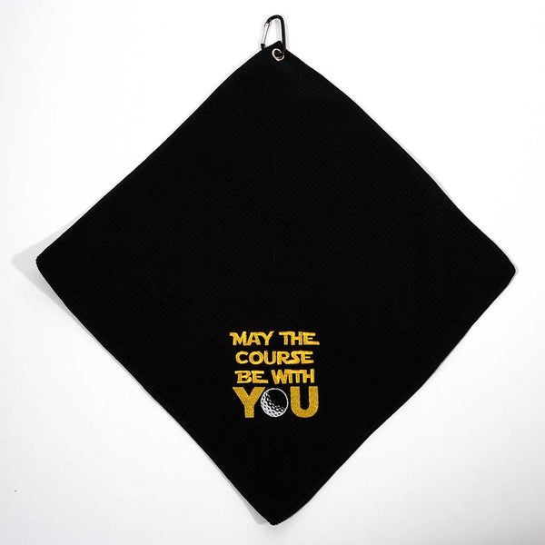 Black towel with 'May the course be with you' text in gold on a white background