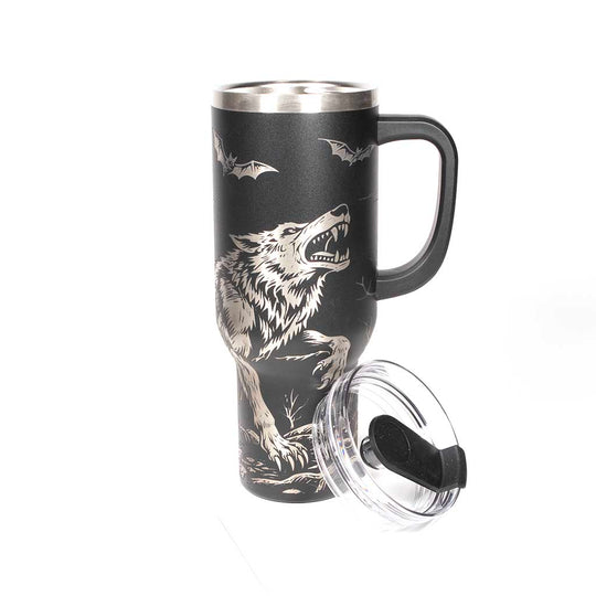 40 ounce travel mug with a werewolf, bats and a gothic cathedral design on a black background. With cover off and straw beside the tumbler. 