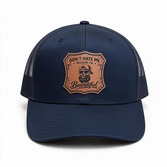 A navy blue trucker hat with a structured front panel and mesh back, featuring a tan shield-shaped patch on the front with a bearded man wearing a hat and the text &