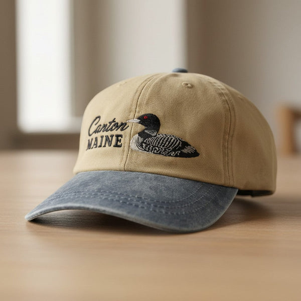 Dailey Woodworking tan and blue cotton hat with embroidered Canton Maine text and a detailed loon illustration.