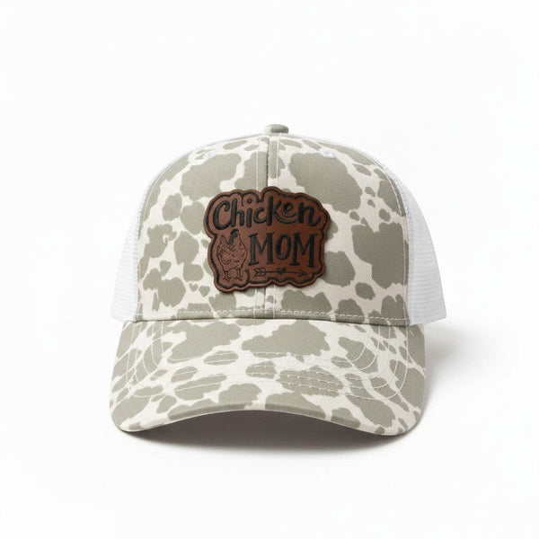 Dailey Woodworking grey cow print trucker hat with "Chicken Mom" leatherette patch and white mesh back.