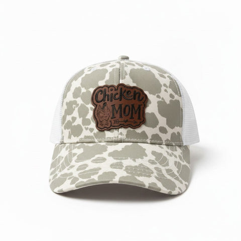 Dailey Woodworking grey cow print trucker hat with "Chicken Mom" leatherette patch and white mesh back.
