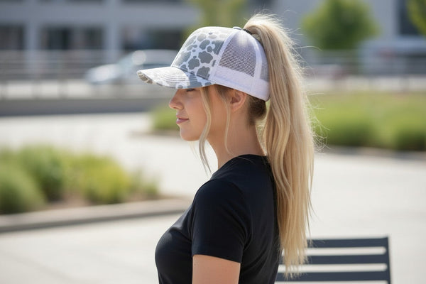 Dailey Woodworking grey cow print trucker hat with white mesh back and ponytail opening.