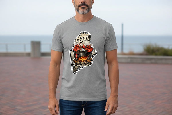 Gravel colored t-shirt with a graphic of the state of Maine containing a lobster pot over a fire with lobsters sitting inside and the words "Ayuh" and "The way life should be"
