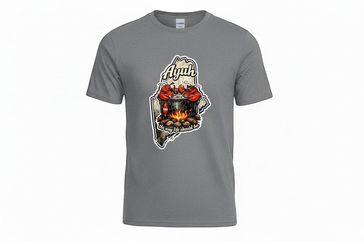 Gravel colored t-shirt with a graphic of the state of Maine containing a lobster pot over a fire with lobsters sitting inside and the words "Ayuh" and "The way life should be"