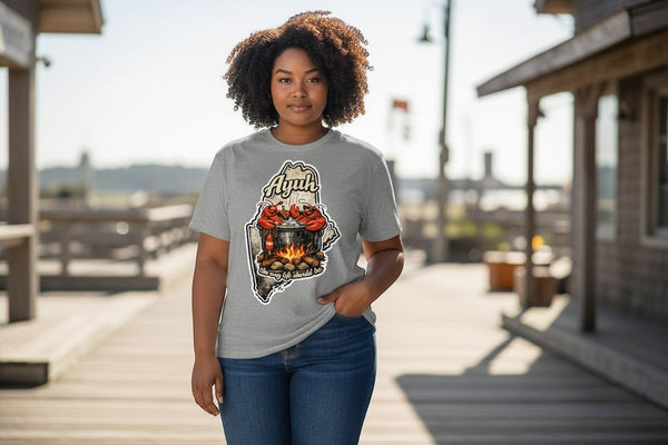 Gravel colored t-shirt with a graphic of the state of Maine containing a lobster pot over a fire with lobsters sitting inside and the words "Ayuh" and "The way life should be"