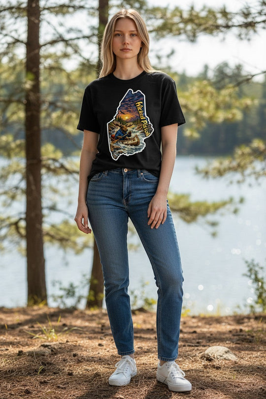 Dailey Woodworking black unisex t-shirt with a graphic of a moose in a canoe on a river at sunset, within the outline of Maine.