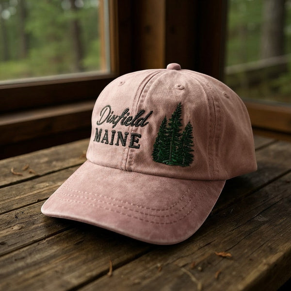 Dailey Woodworking dusty pink cotton hat with Dixfield Maine script and embroidered pine tree design.