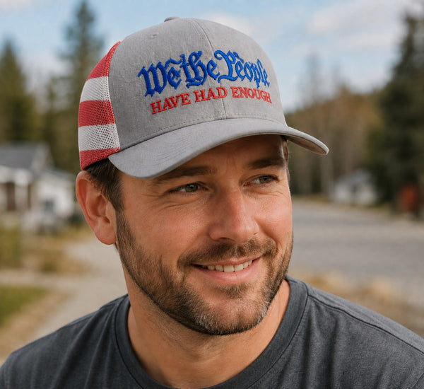 Dailey Woodworking trucker hat with heather grey front, stars-and-stripes mesh back, and We The People embroidery.