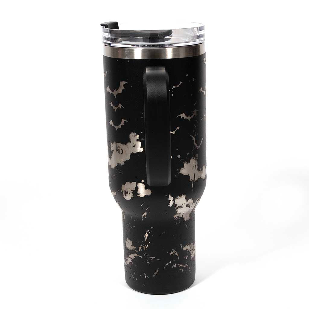 This is a black 40 ounce tumbler with a screw on lid with a drinking hole access and a straw. The laser engraving is of a witch flying on her broom above a home and pumpkin patch. Side 4