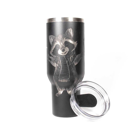 40 ounce black travel mug with three engraved raccoons dressed in scarves and hats. With cover leaned up against tumbler. 