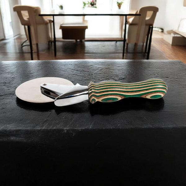 Camo Laminated Pizza Cutter, Pizza Wheel sitting on a black counter with table and chairs in background - Dailey Woodworking
