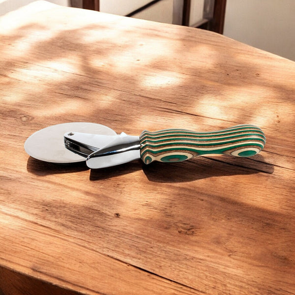 Camo Laminated Pizza Cutter, Pizza Wheel sitting on a wooden table with a chair in background - Dailey Woodworking