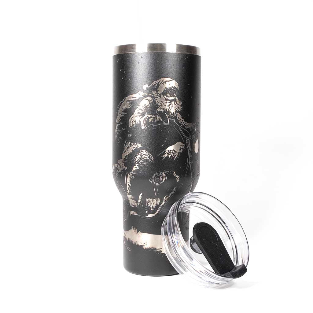 Black 40 ounce travel mug with an laser engraving of Santa taking off into the night on his trusty motorcycle. With cover off