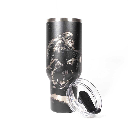 Black 40 ounce travel mug with an laser engraving of Santa taking off into the night on his trusty motorcycle. With cover off