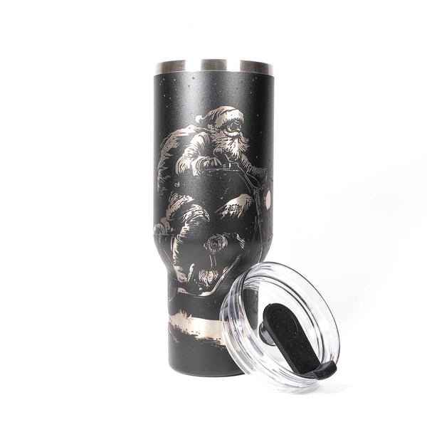 Black 40 ounce travel mug with an laser engraving of Santa taking off into the night on his trusty motorcycle. With cover off